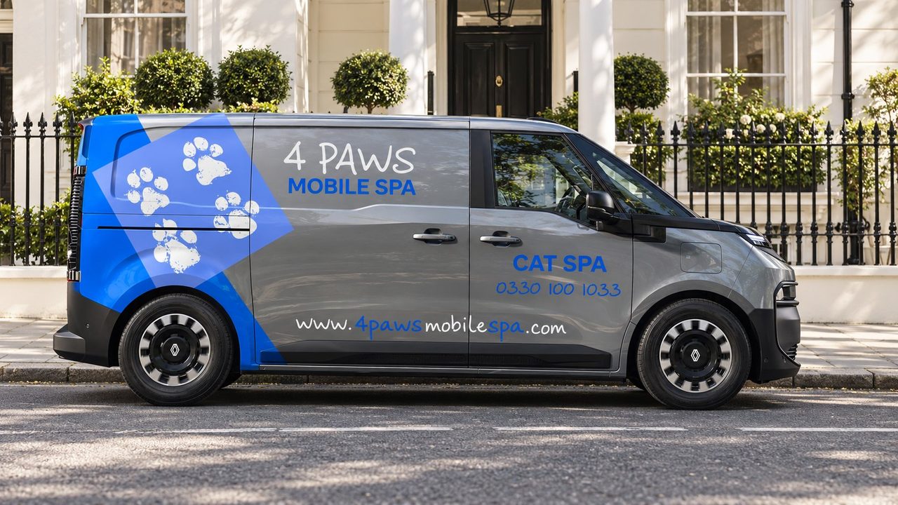 Side view of a 4 Paws Mobile Cat Spa on a white stucco street